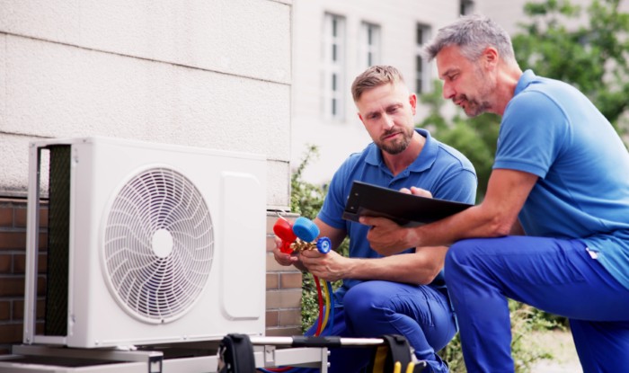 HVAC technicians reviewing an outdoor air conditioning unit in Gilbert, AZ
