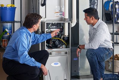 HVAC technician explaining furnace repair and maintenance to a homeowner in Gilbert, AZ