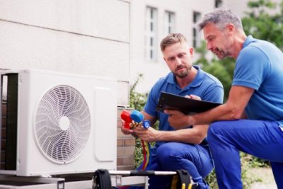 HVAC technicians reviewing an outdoor air conditioning unit in Gilbert, AZ